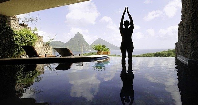 person doing yoga in front of their private plunge pool in their hotel room overlooking mountains and the ocean